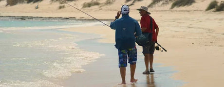 Two men beach fishing at sunset, casting lines from a sandy shoreline as they refine their skills in surf fishing for the Beach Mastery blog