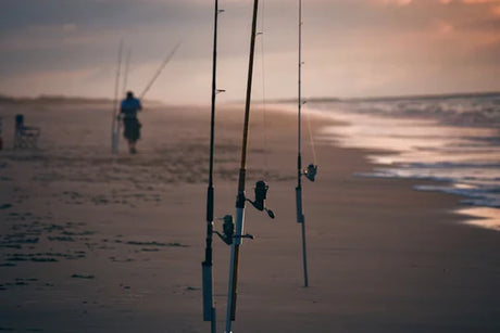 Fisherman setting up rods on beach, preparing for a successful beach fishing session with essential gear and techniques