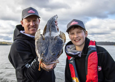 Anglers smiling and holding their flathead catch, celebrating successful fishing techniques from a comprehensive guide with pro tips