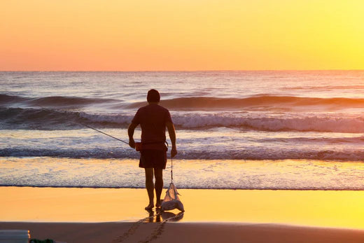 Angler dragging berley along the sandy beach at dawn, setting up for a successful fishing session